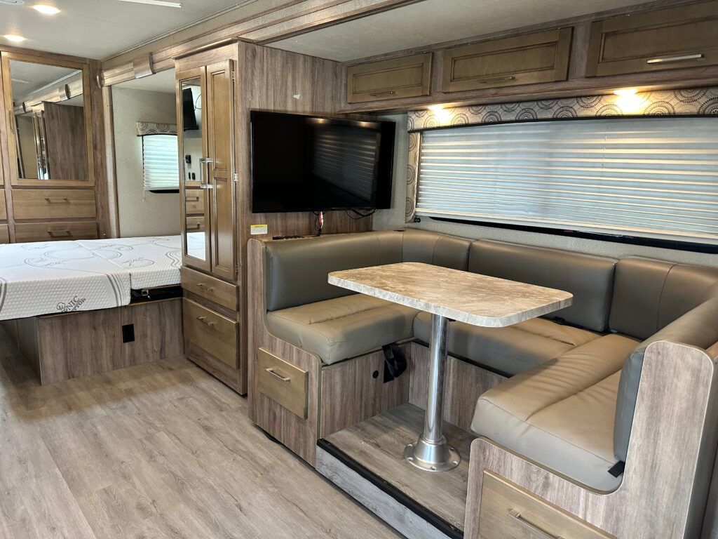 A living room in a rv with a table and a flat screen tv.