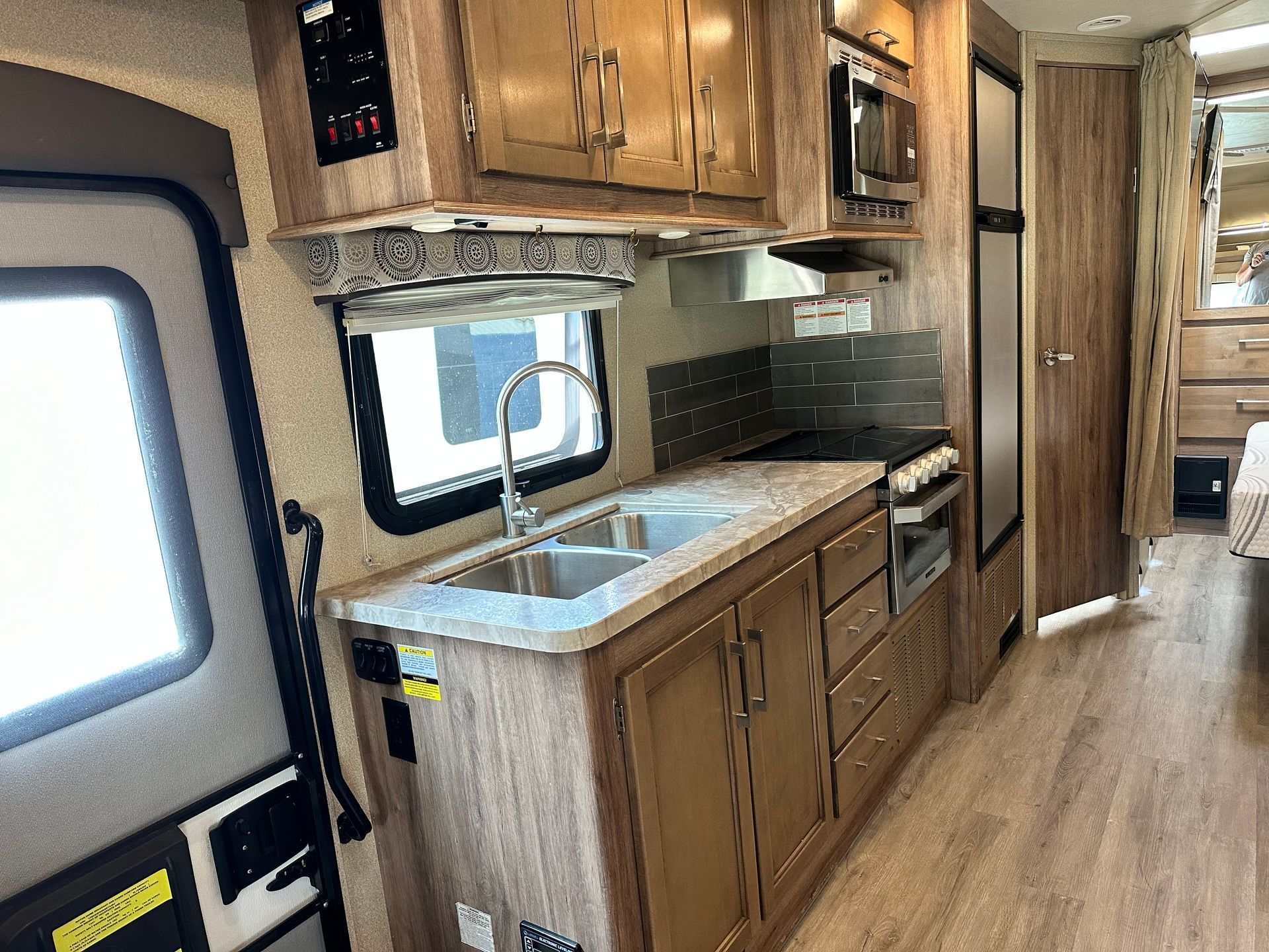 A kitchen in a rv with a sink , stove , microwave and refrigerator.