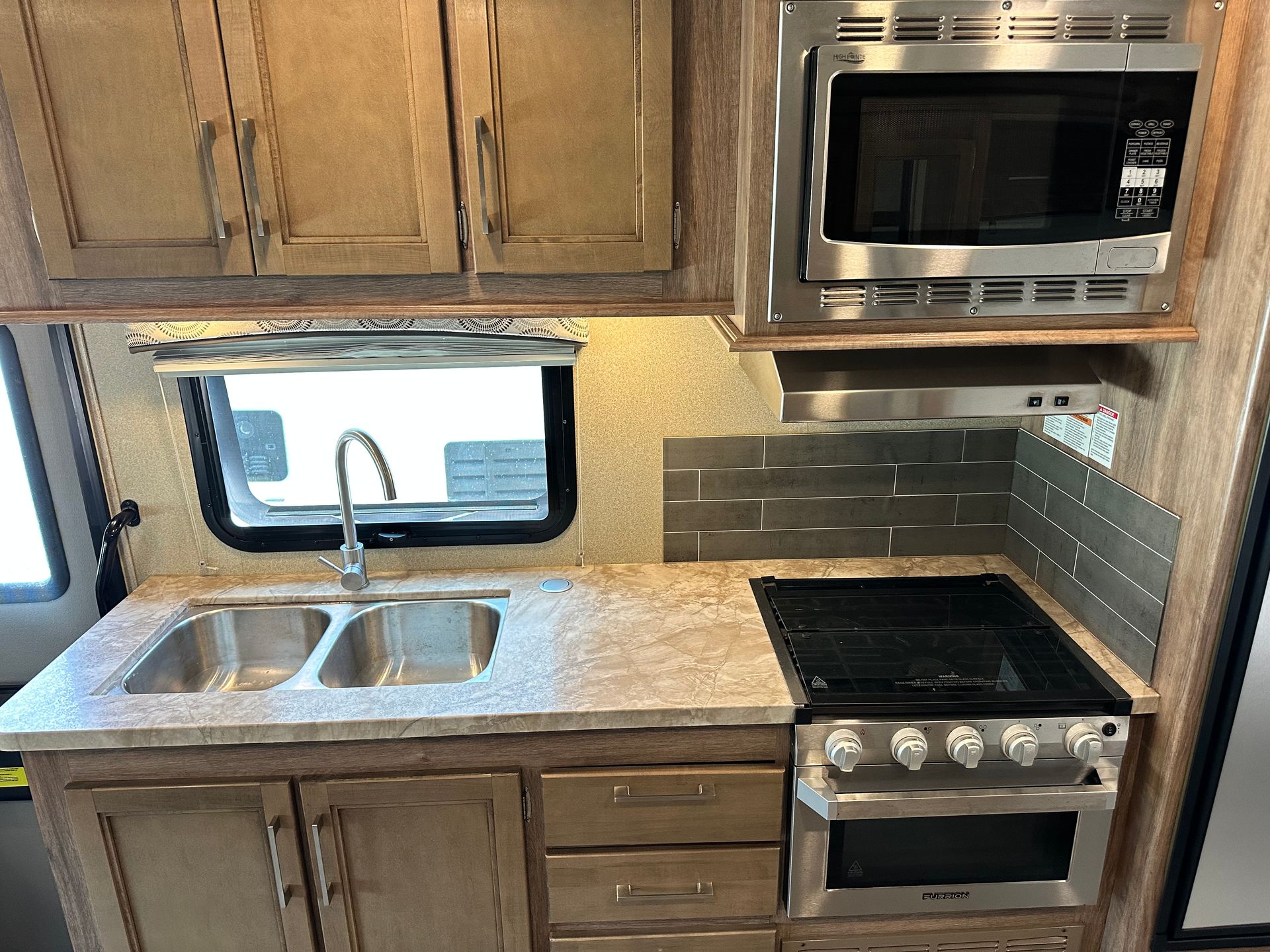 A kitchen in a rv with a sink stove and microwave