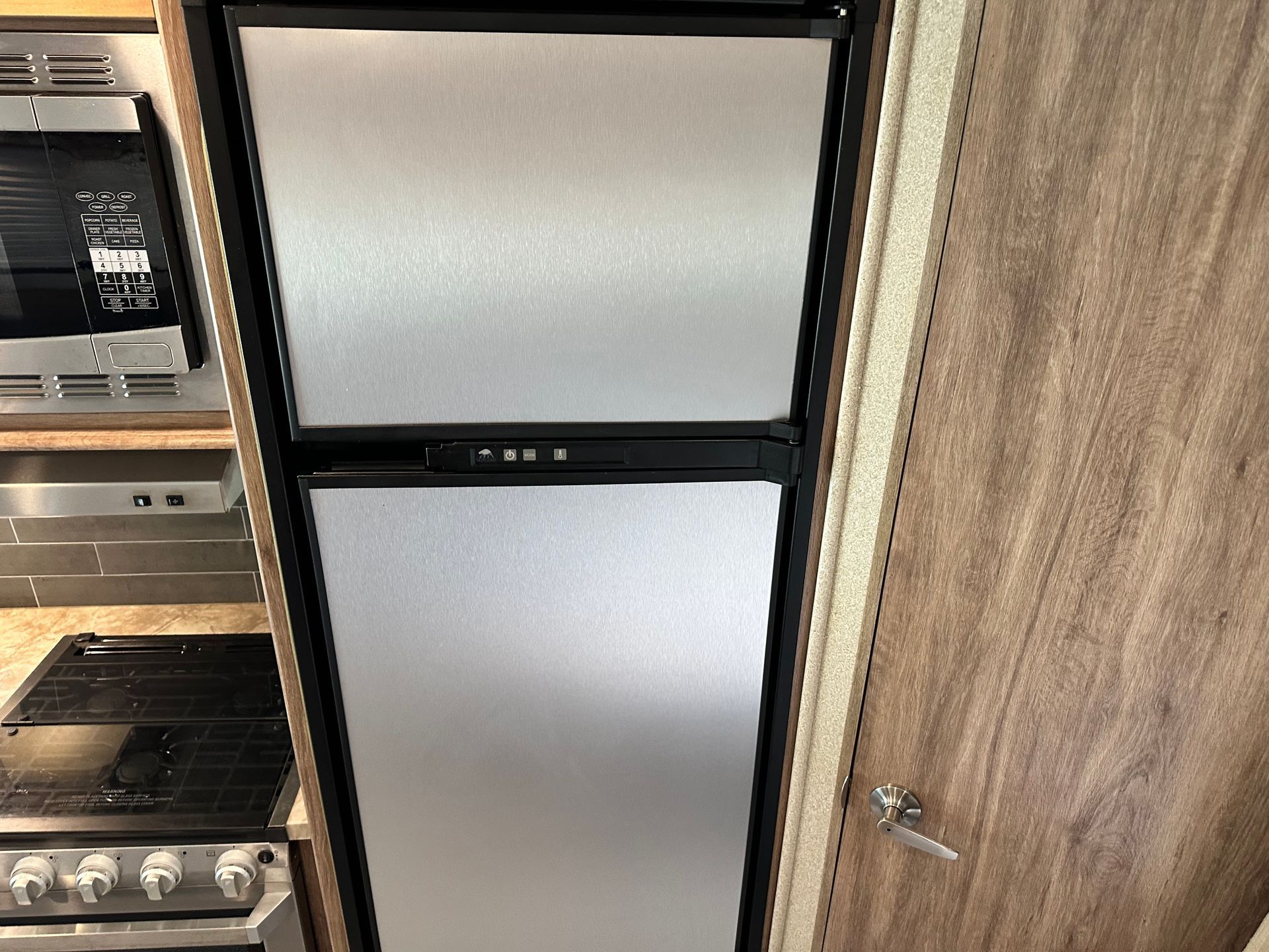 A stainless steel refrigerator in a kitchen next to a stove