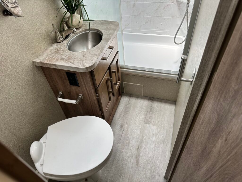 A bathroom with a toilet , sink and shower.