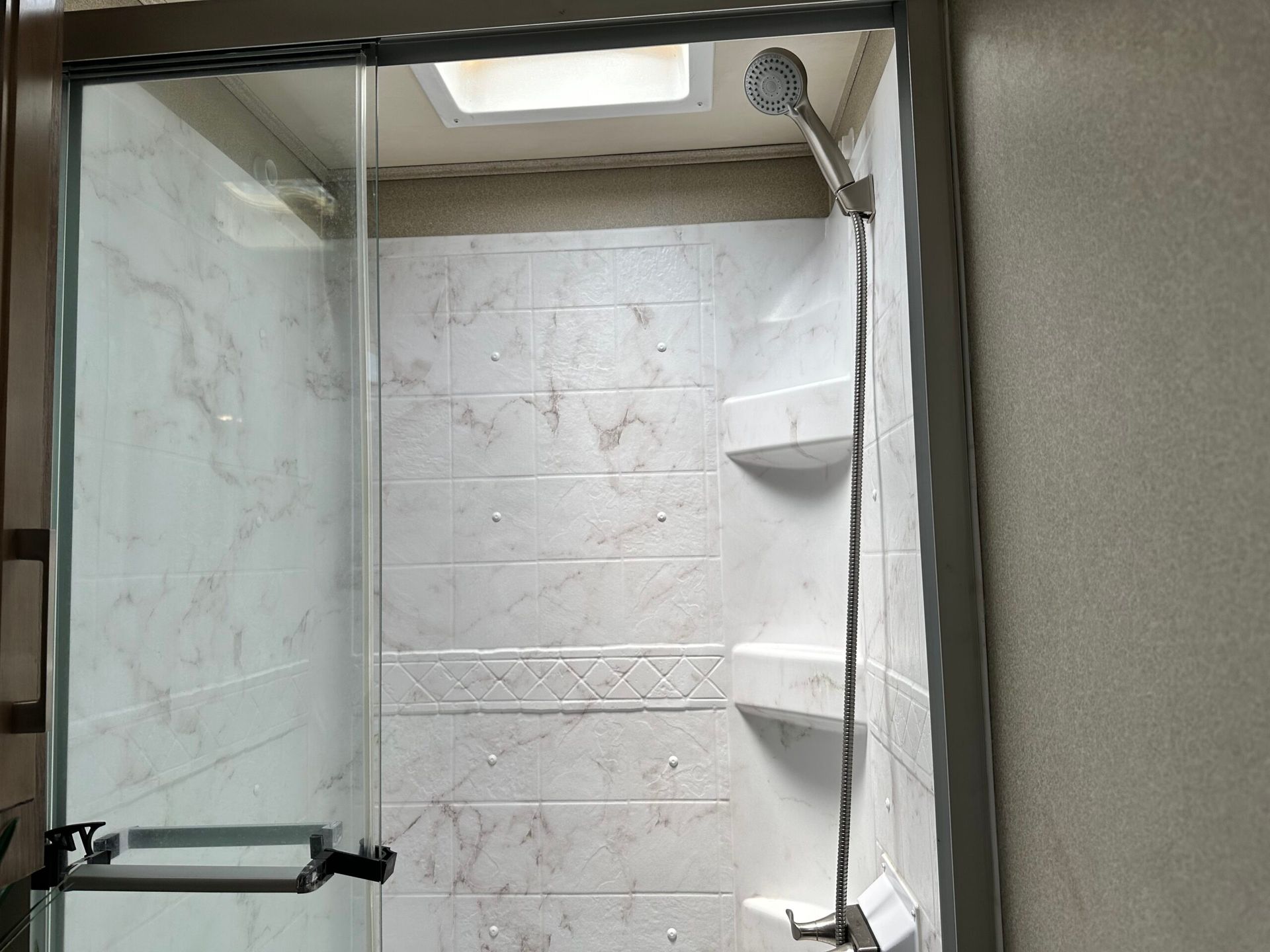 A shower with a sliding glass door and a shower head.