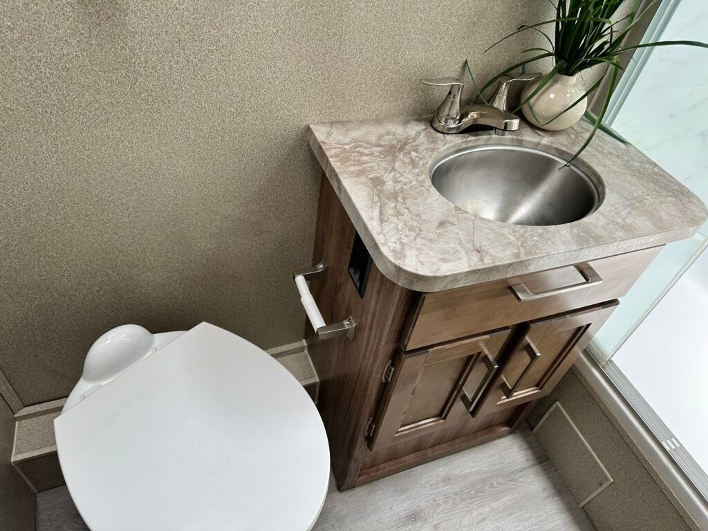 A bathroom with a toilet , sink and cabinets.