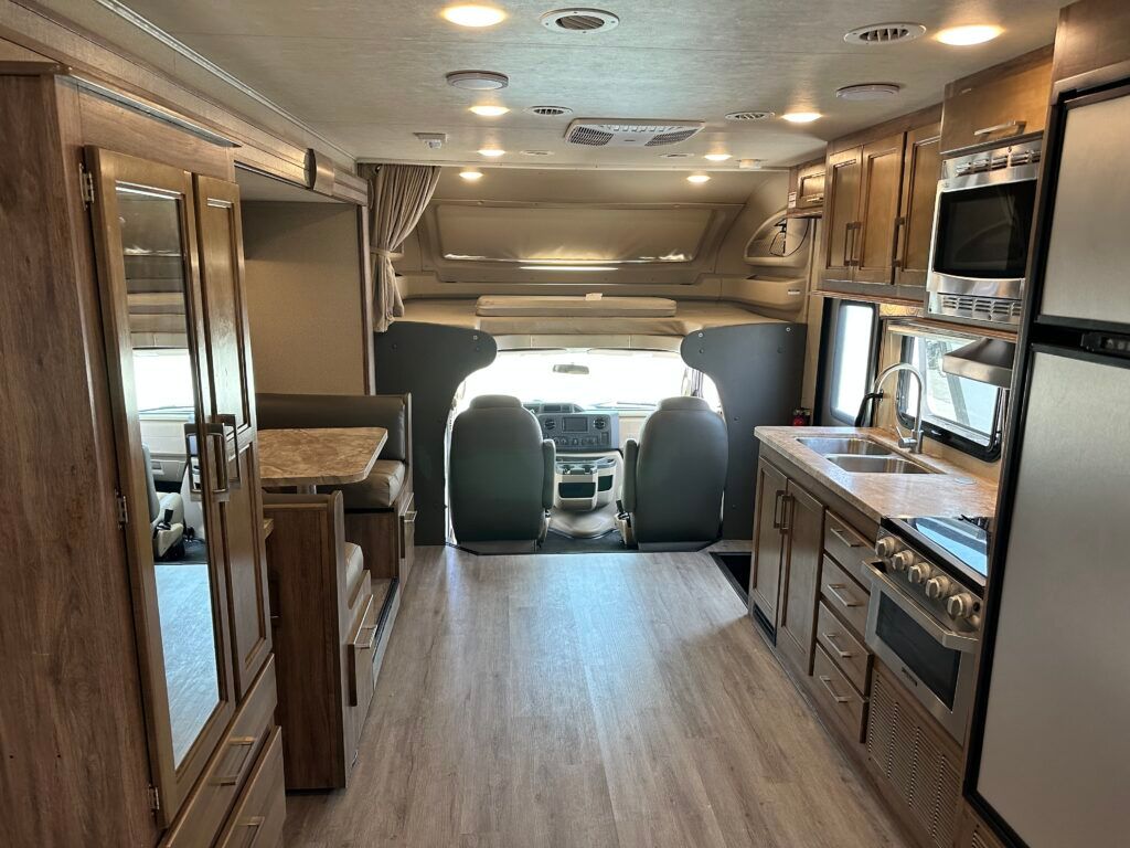 The inside of a rv with a kitchen and a bed.