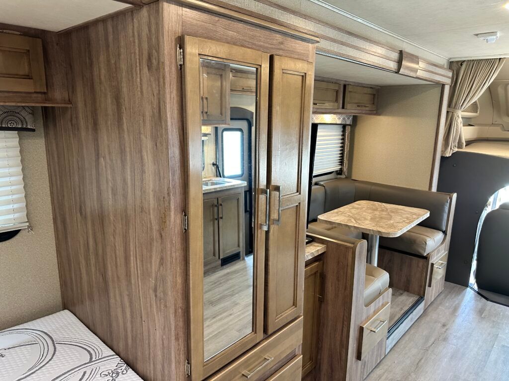 The inside of a rv with a wardrobe and a table.