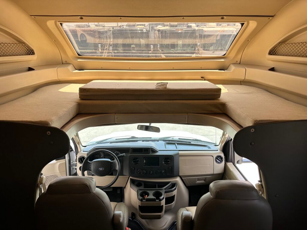 The inside of a camper van with a bed and a steering wheel.