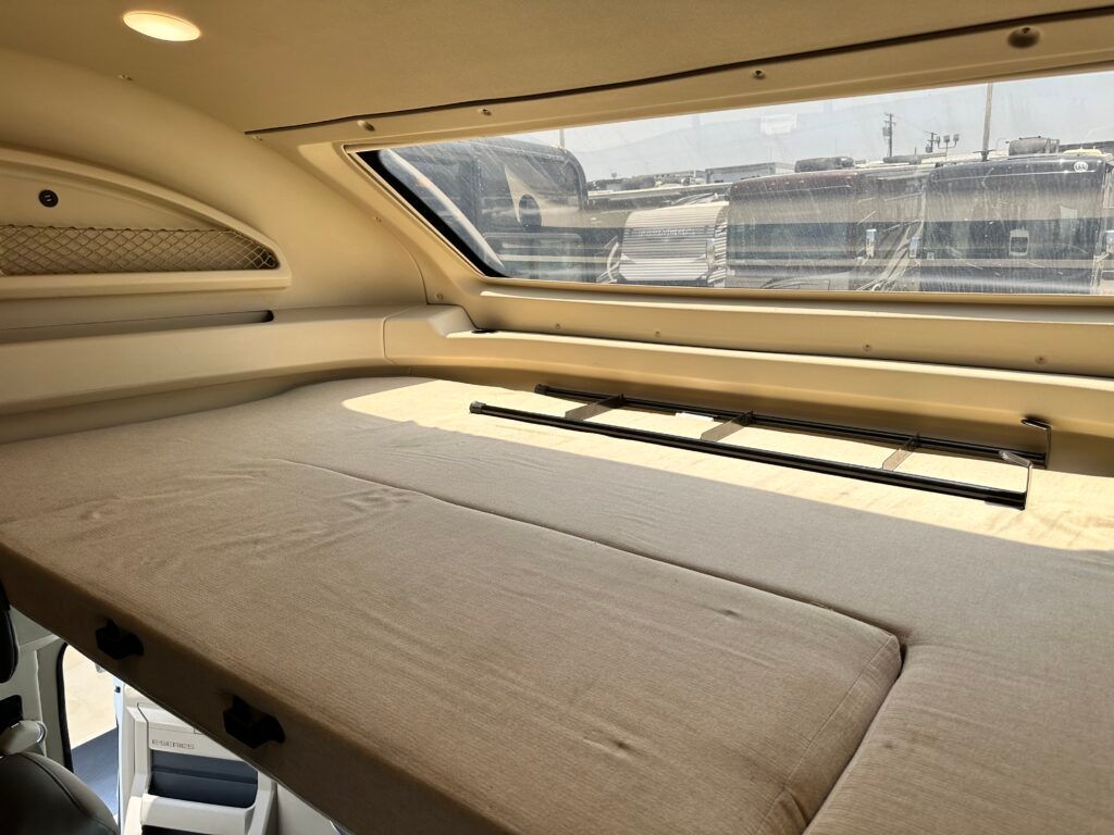 A bed with a window in the back of a vehicle.