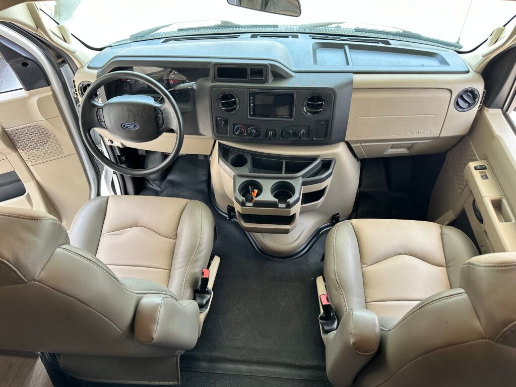 The interior of a van with tan leather seats and a steering wheel.