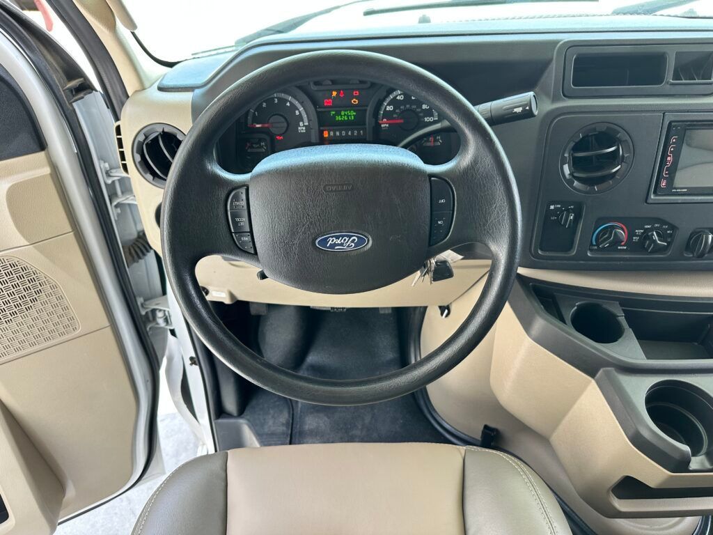 The interior of a ford van with the door open and the steering wheel visible.