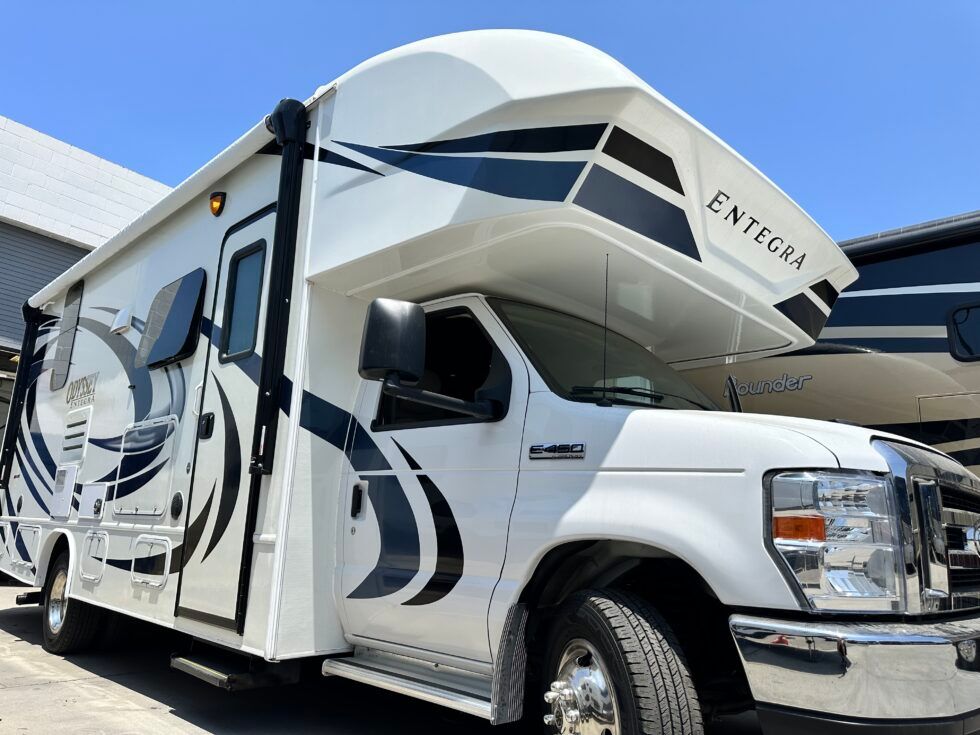 A white rv with the hood up is parked in a parking lot.