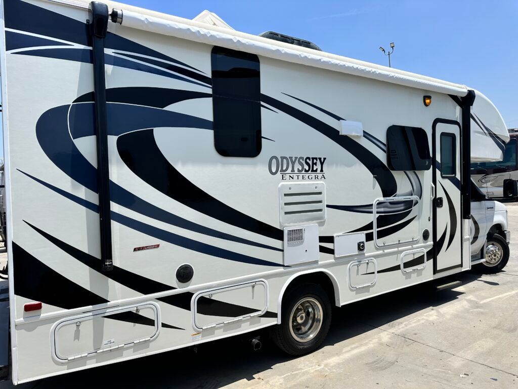 A white and black rv is parked in a parking lot.