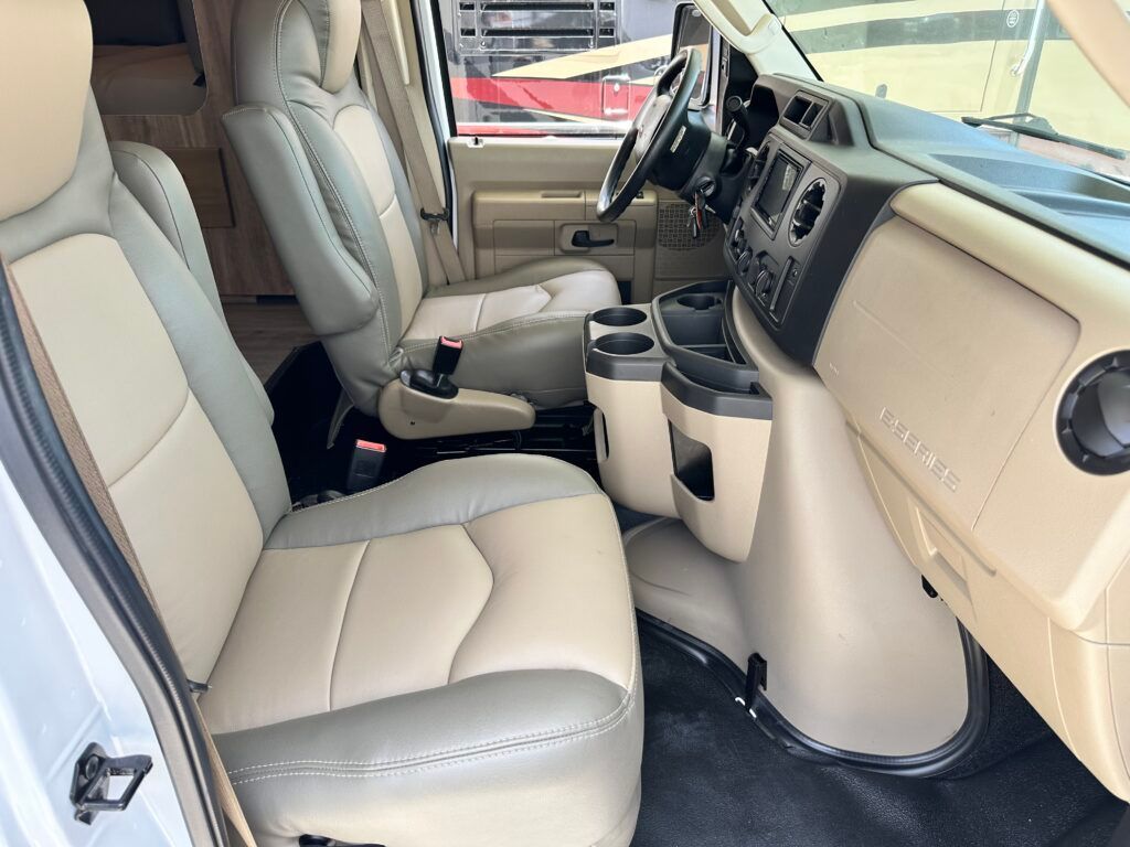 The interior of a van with tan leather seats and a steering wheel.