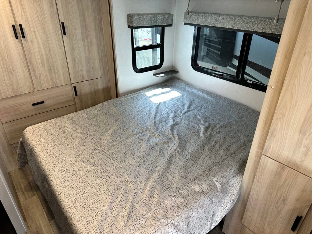 A bedroom in a rv with a bed and a window.