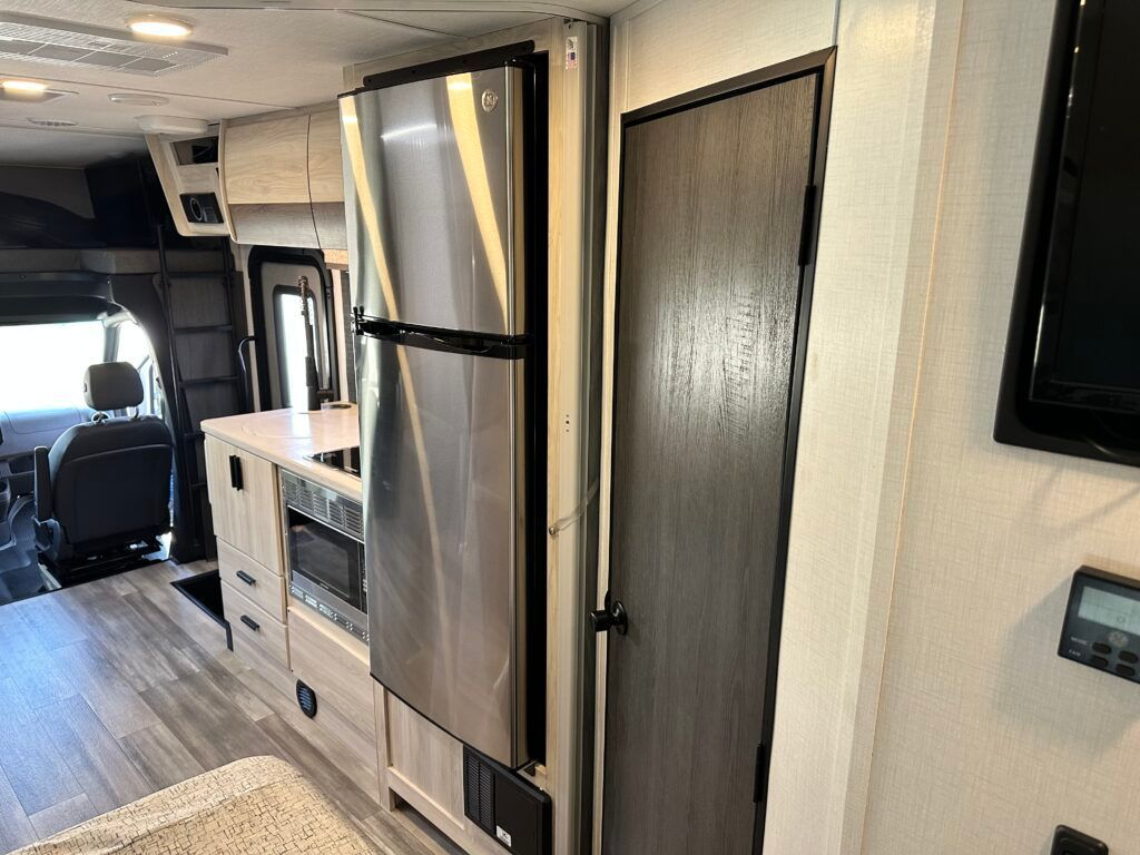 A rv with a refrigerator and microwave in the kitchen.