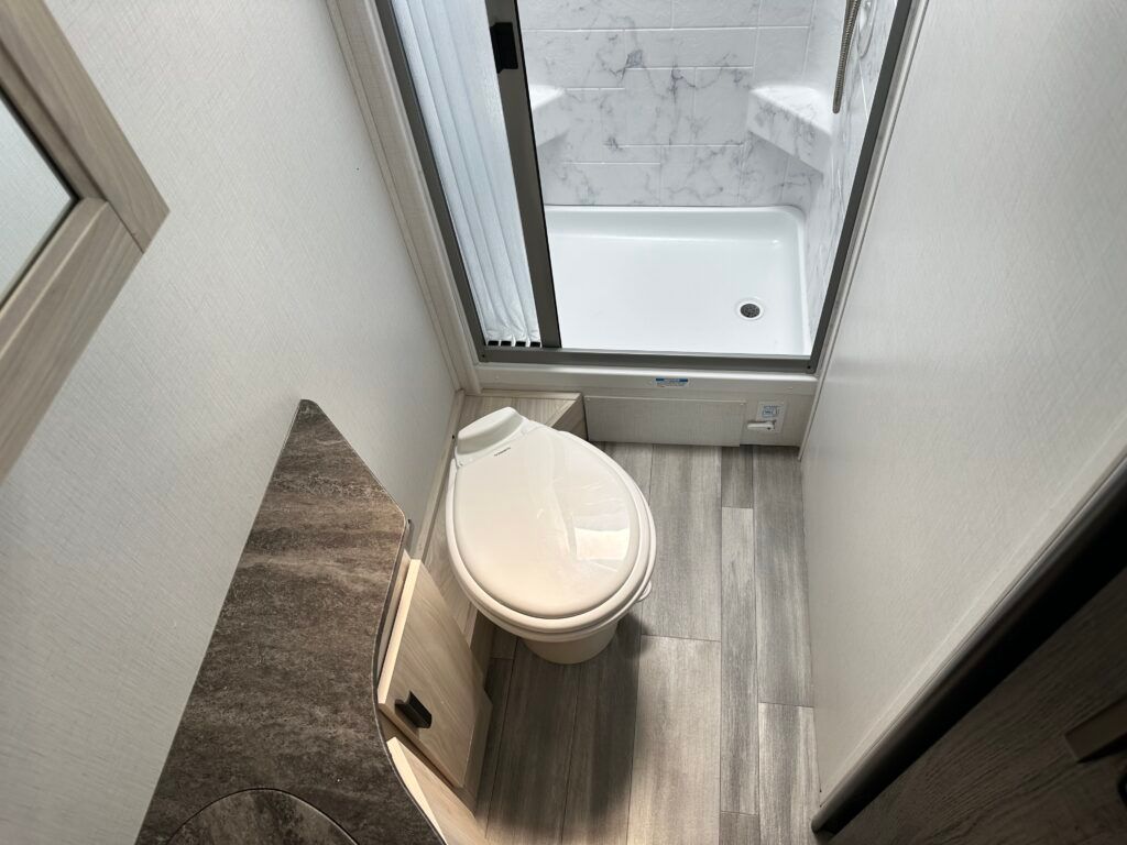 A bathroom with a toilet , sink and shower.