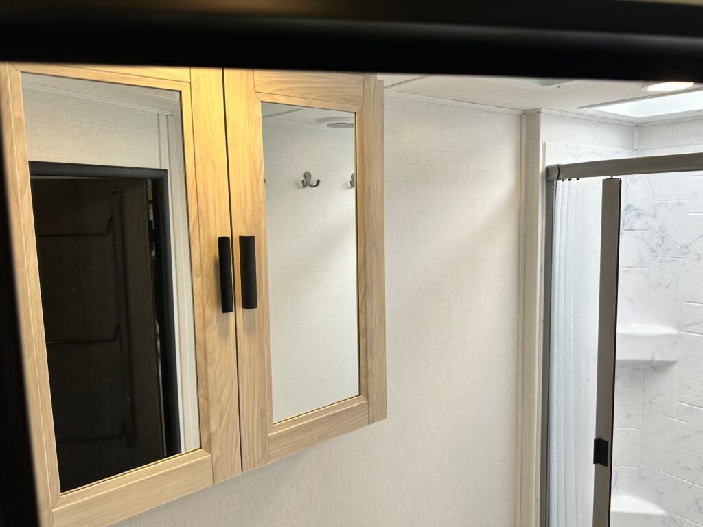 A bathroom with two mirrors and a shower stall.