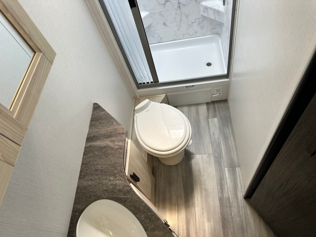 A bathroom with a toilet , sink and shower.