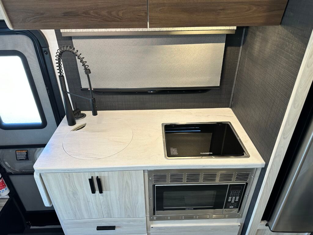 A kitchen with a sink , microwave , and refrigerator.
