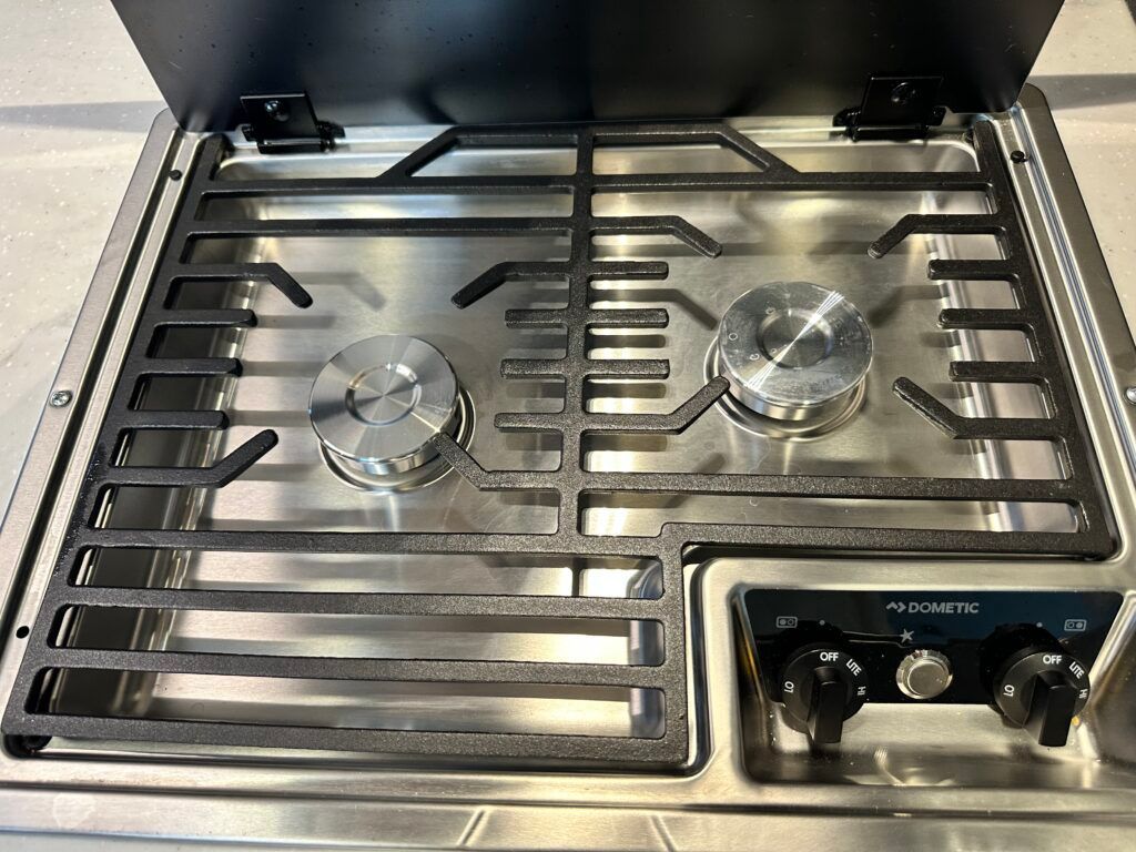 A stainless steel stove top oven with three burners and a grill.