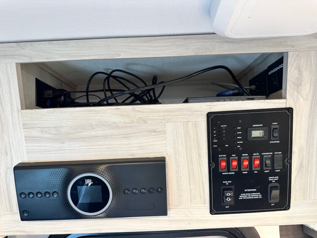 A rv has a shelf with a remote control and electrical outlets.