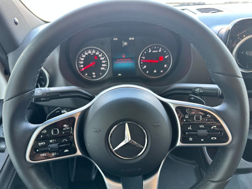 A close up of a mercedes benz steering wheel and dashboard.