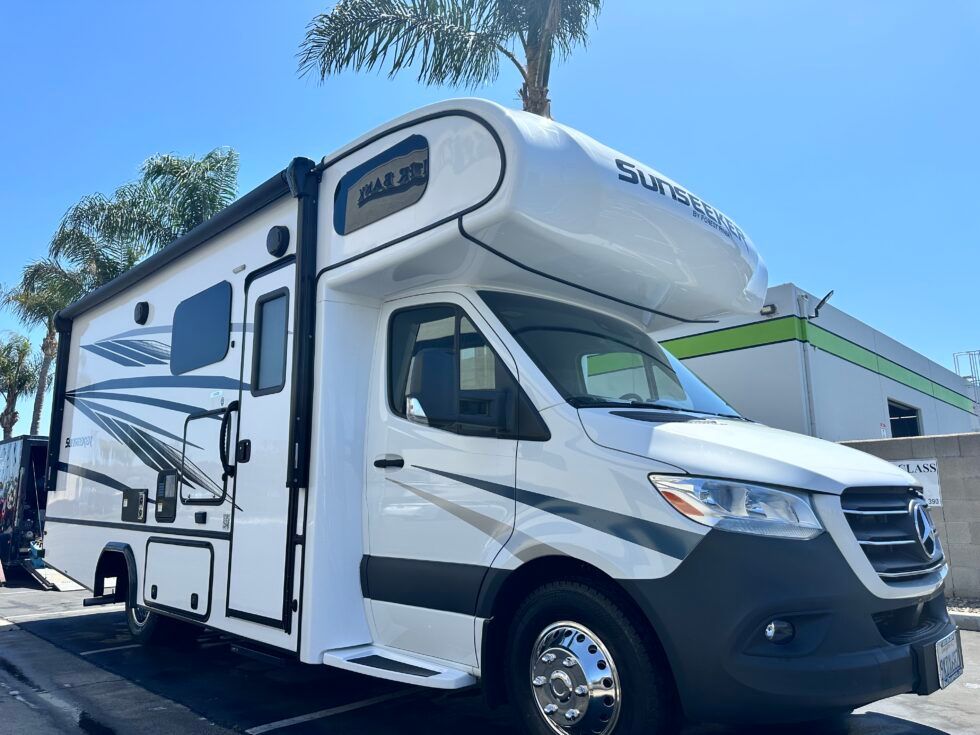 A white rv is parked in a parking lot in front of a building.