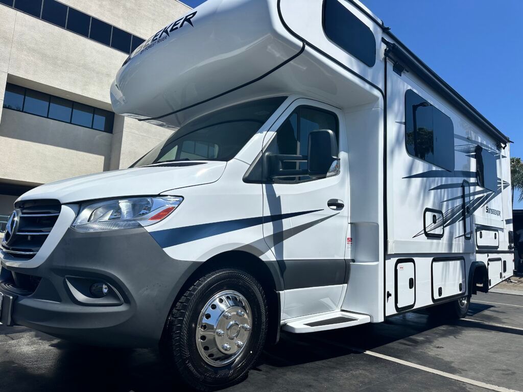 A white rv is parked in a parking lot in front of a building.
