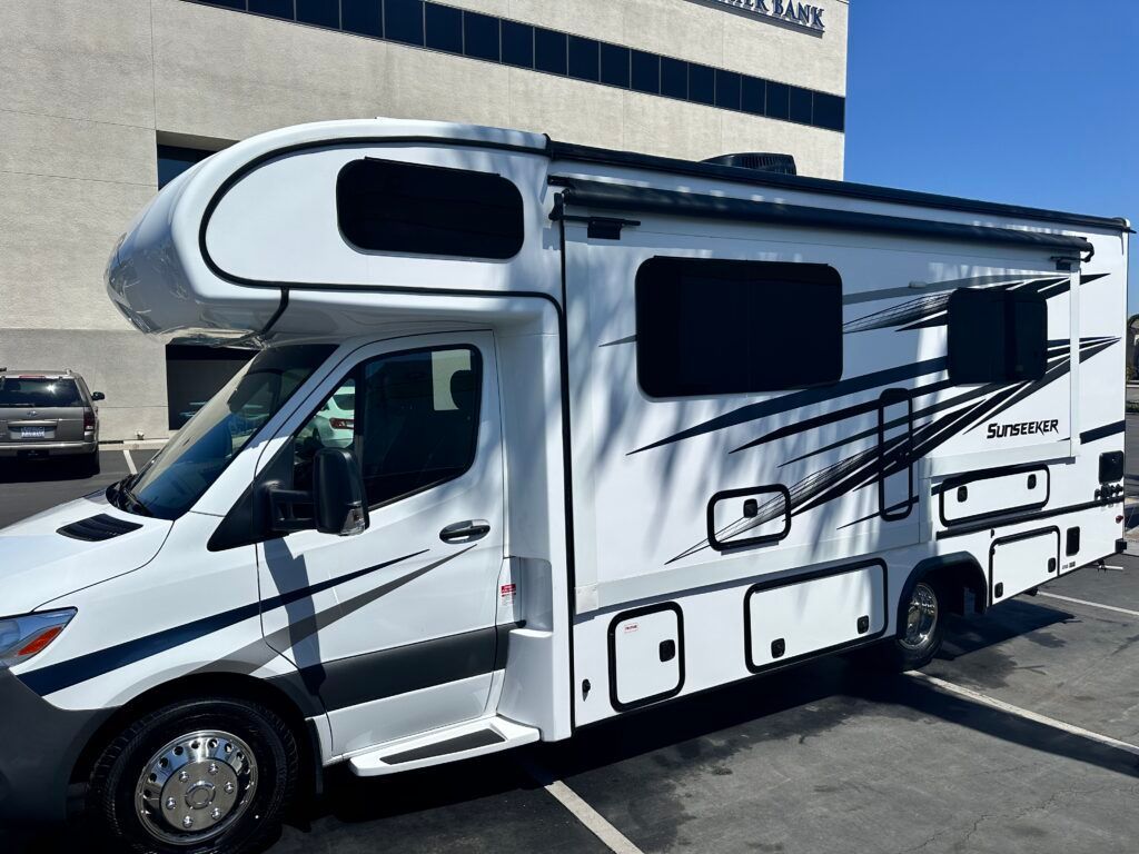 A white rv is parked in a parking lot in front of a building.