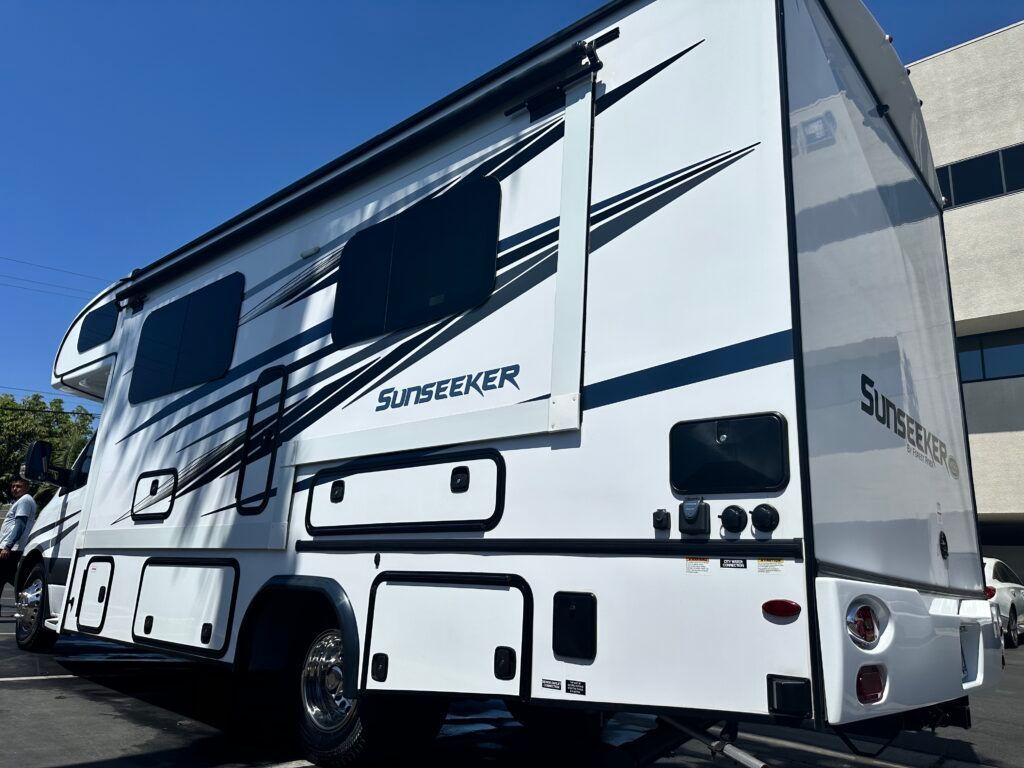A white rv is parked in a parking lot in front of a building.
