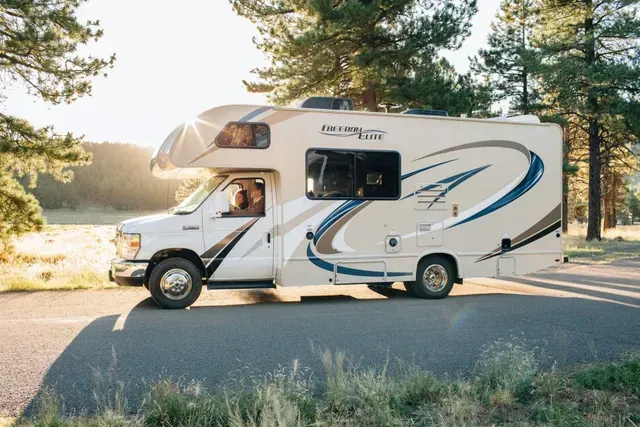 A white rv is parked on the side of the road.