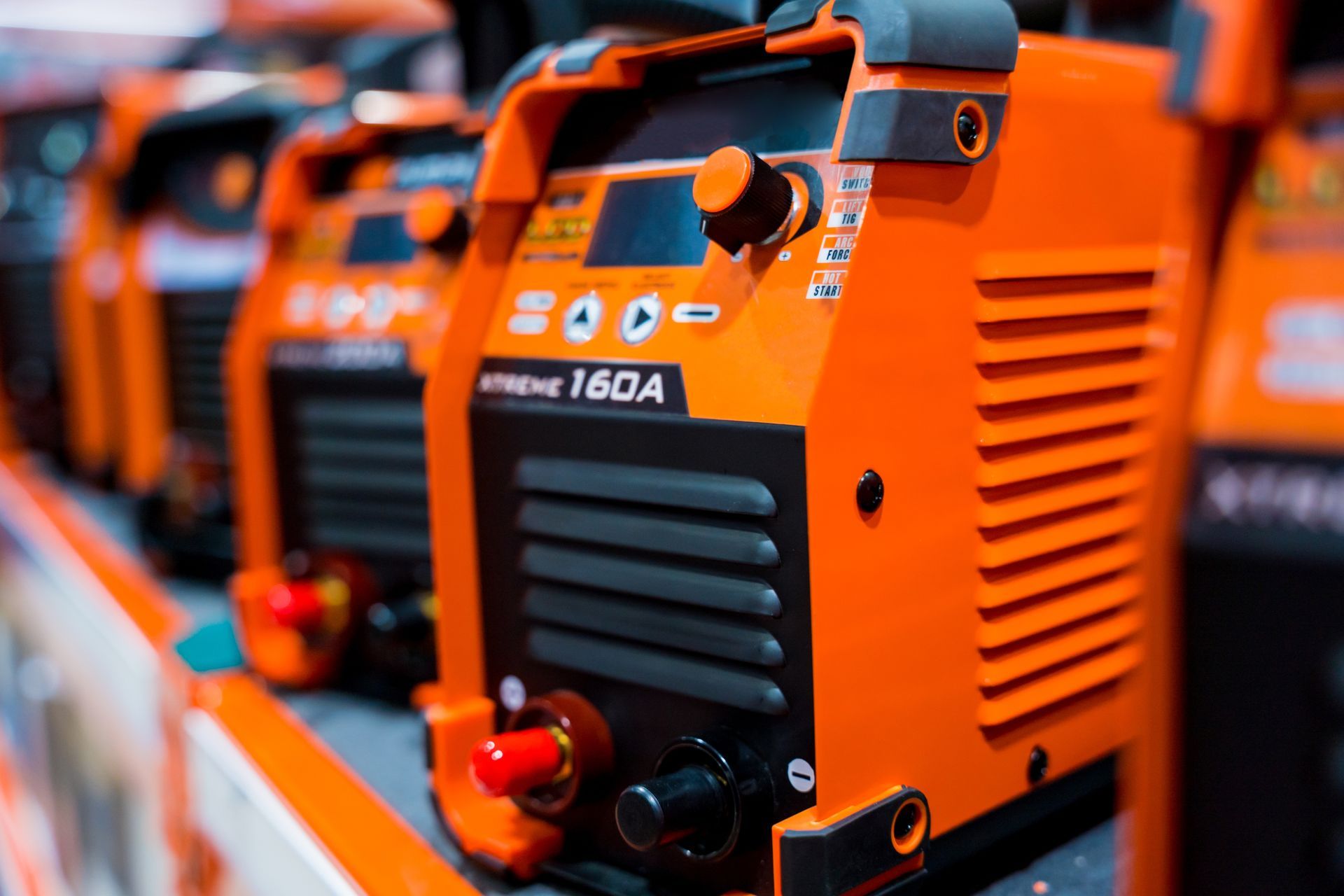 A row of welding machines are lined up on a shelf in a store.