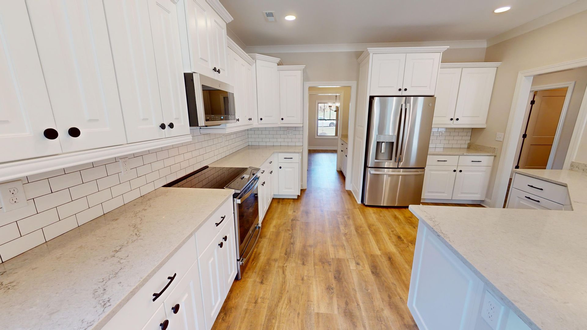 White kitchen with stainless steel appliances, light countertops, and wood floors.