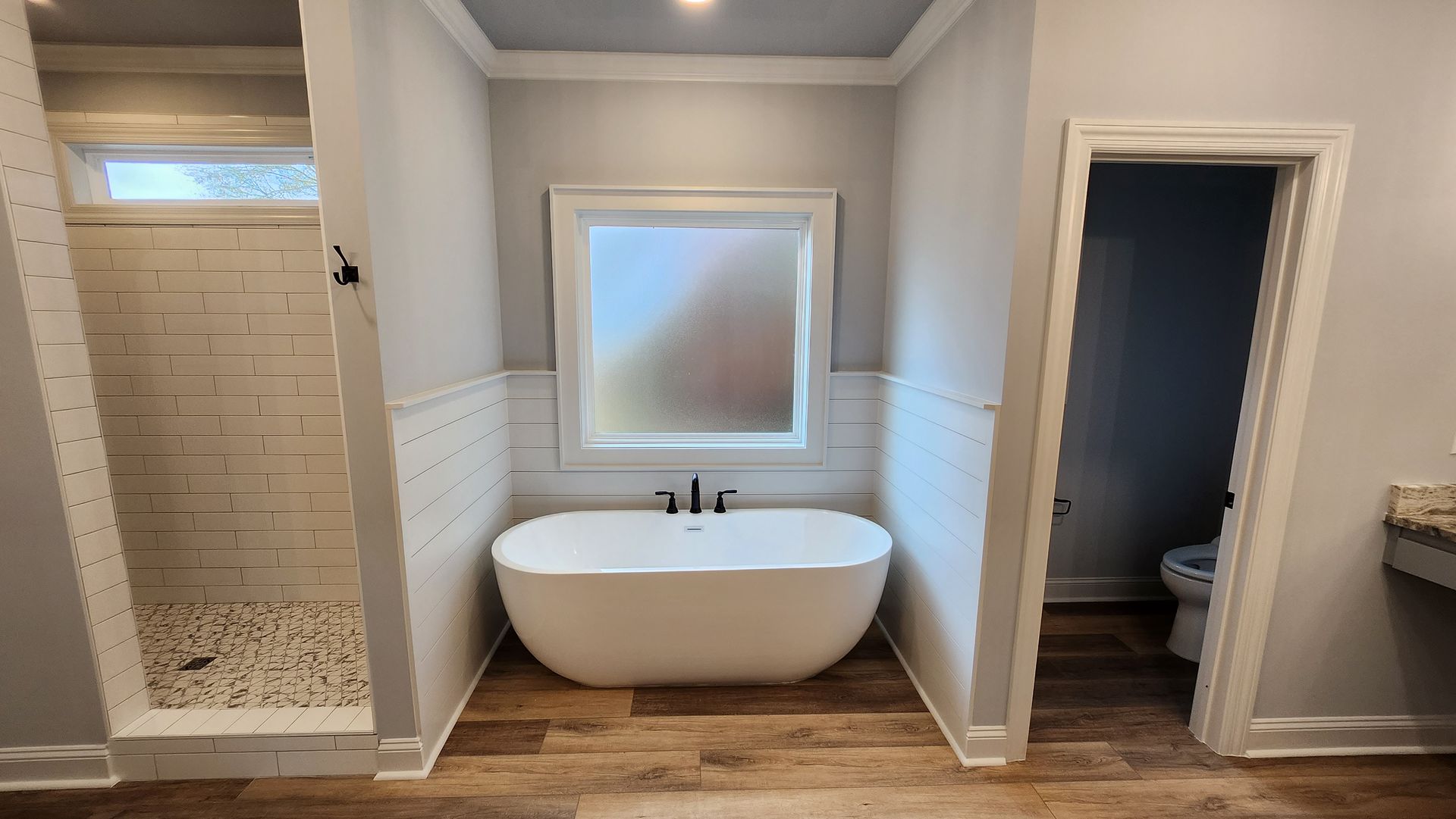 Bathroom with a white freestanding tub, shower, and toilet.