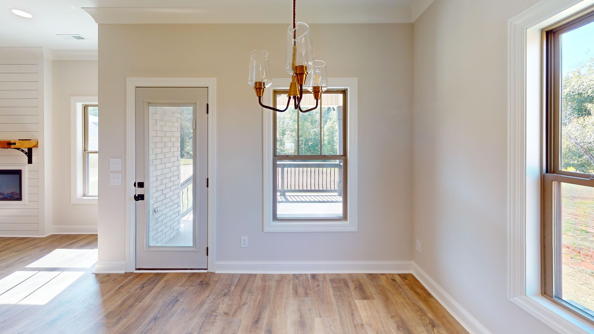 Dining room with wooden floor, chandelier, door, and windows.