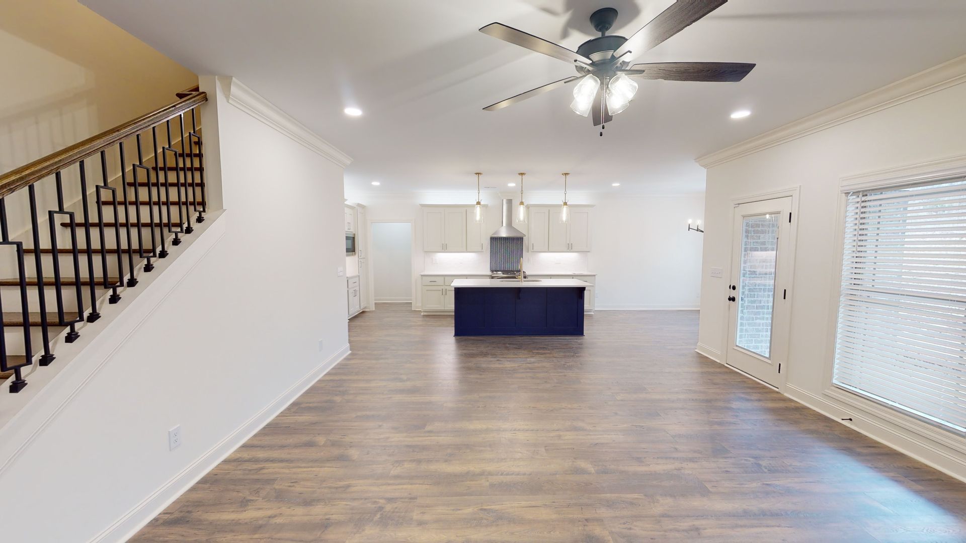 Spacious, bright interior with staircase, open kitchen with blue island, and French doors.