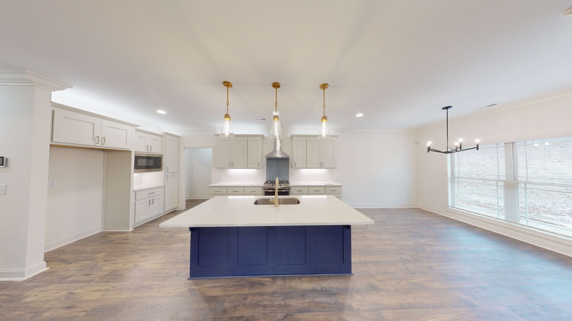Modern kitchen with a blue island, light cabinets, and gold pendant lights.