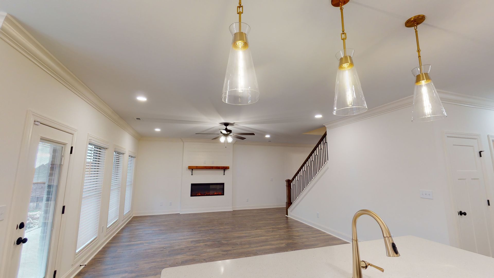 Interior view of a modern living area with a fireplace, staircase, and kitchen island.