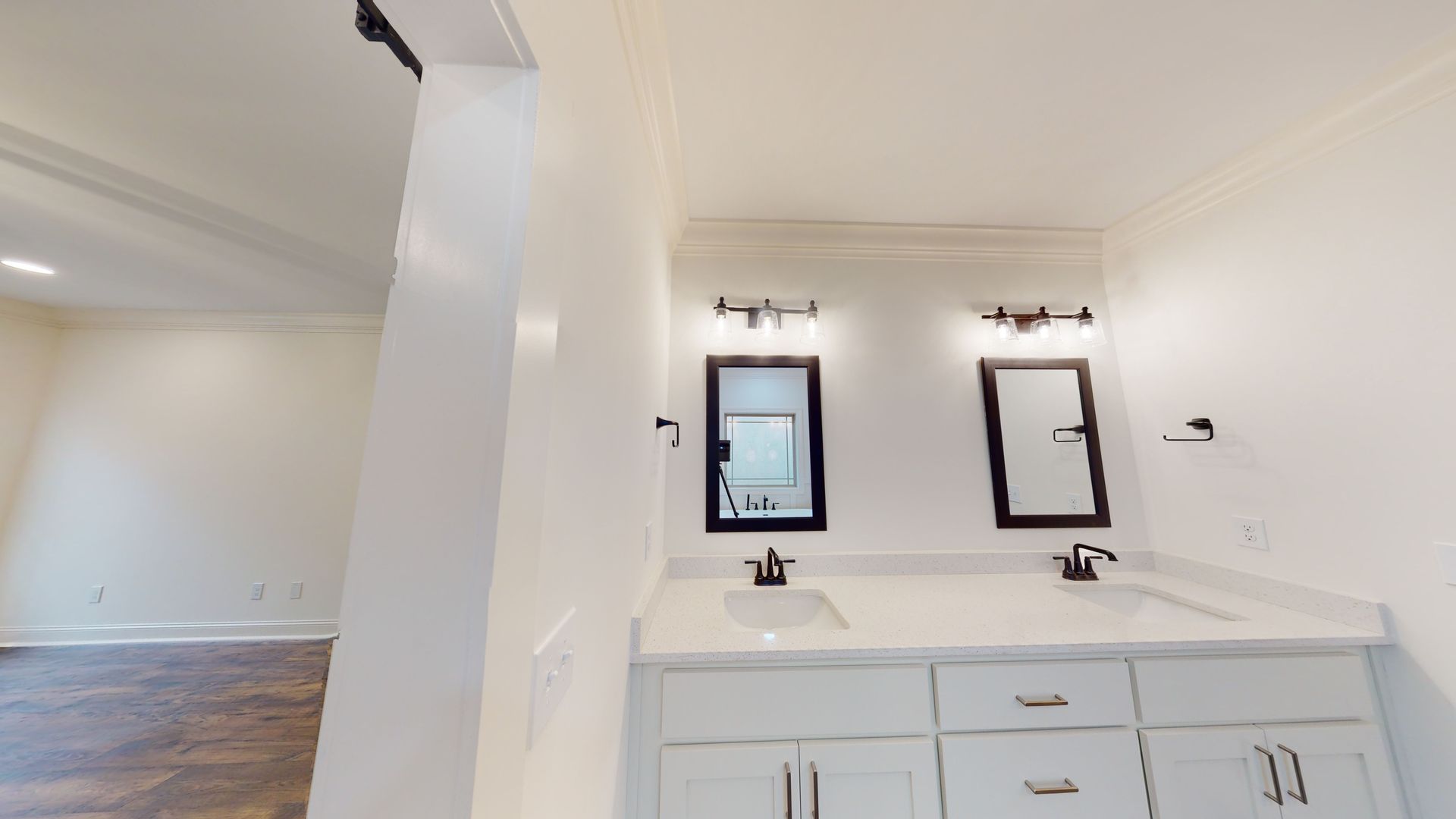 Bathroom with white vanity, two black-framed mirrors, and sconce lighting.
