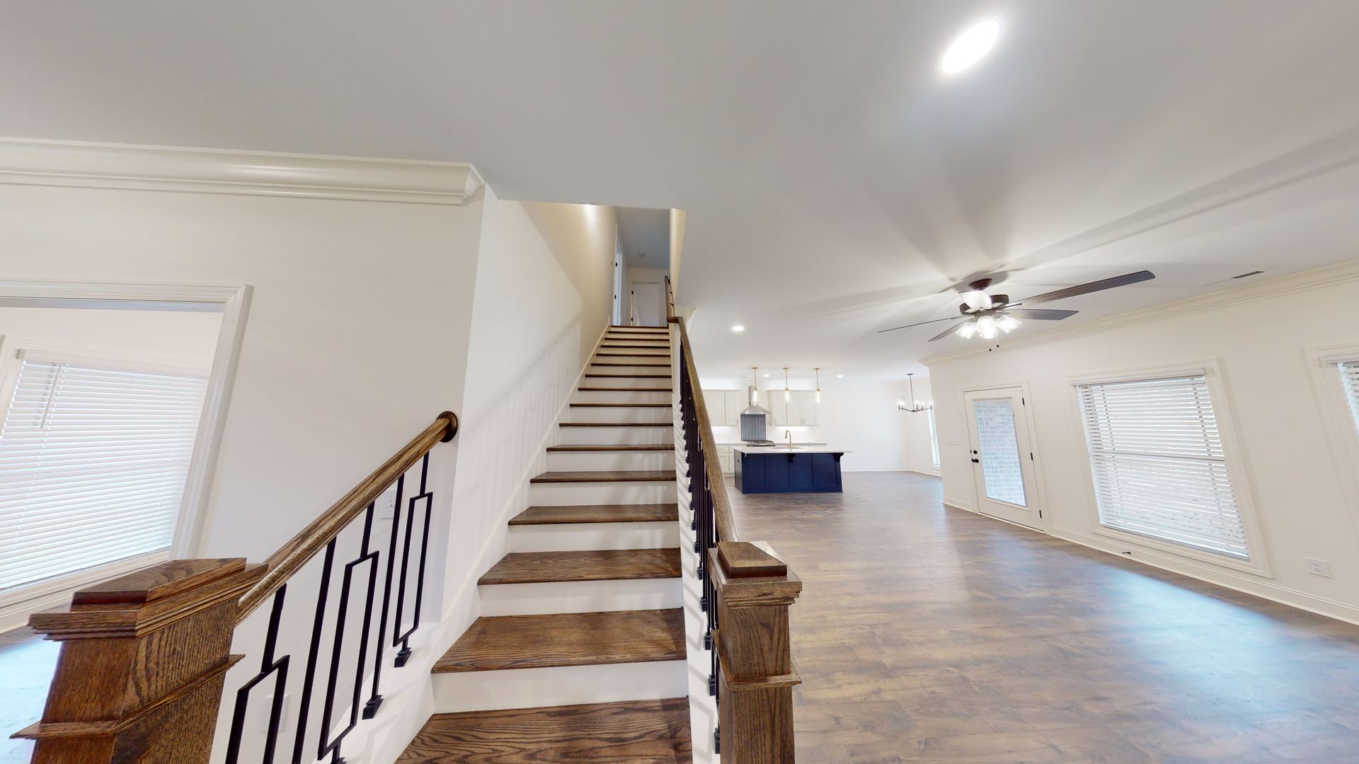 Staircase with wooden handrail, leading up to a second floor, in a spacious, bright room.
