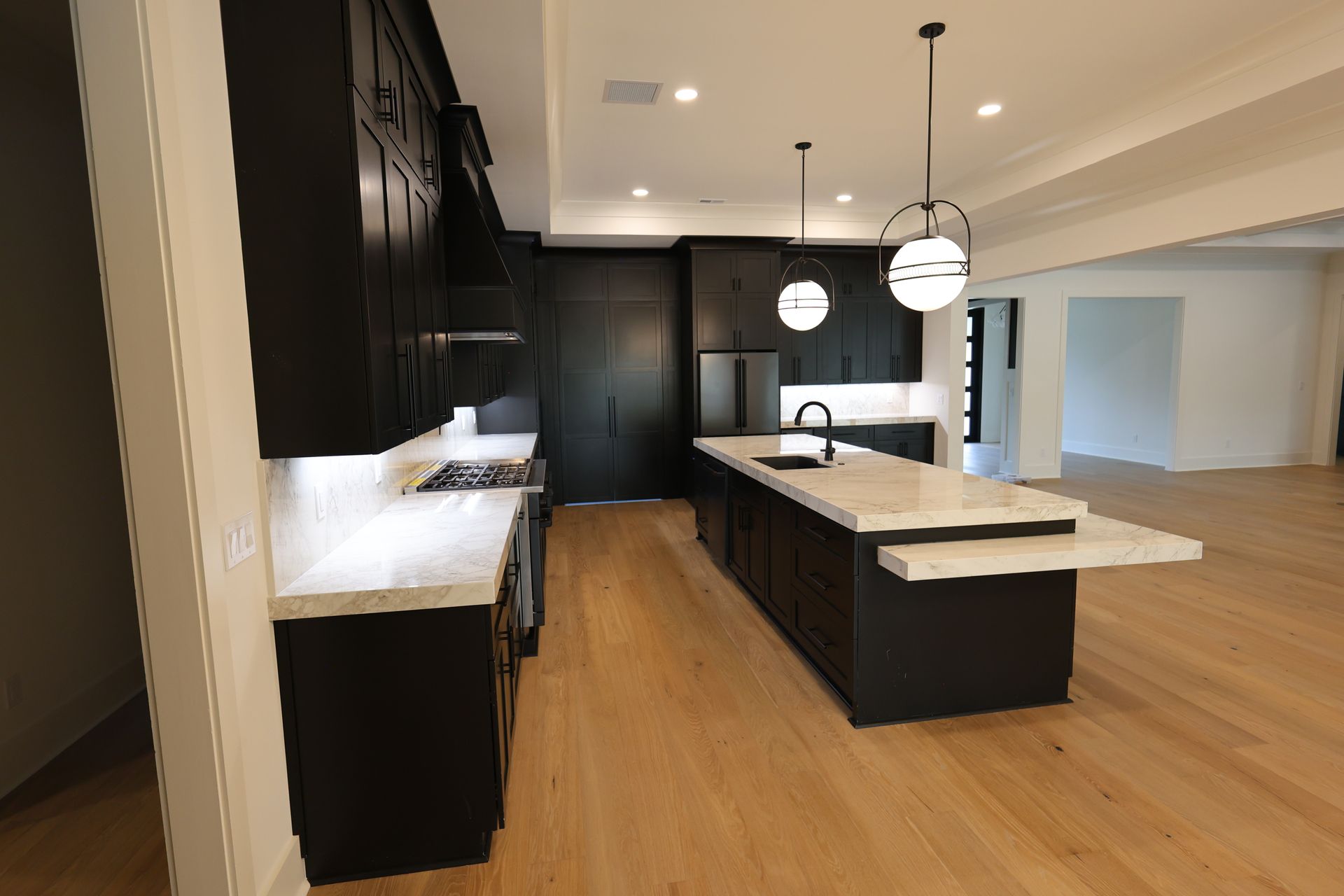 Dark kitchen with island and light countertops. Hardwood floors.