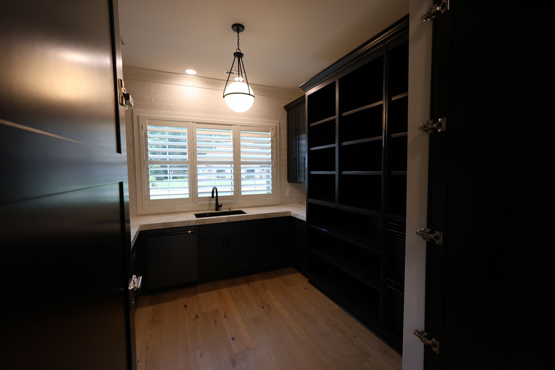 Dark pantry with black cabinets, white countertops, and a window with blinds.