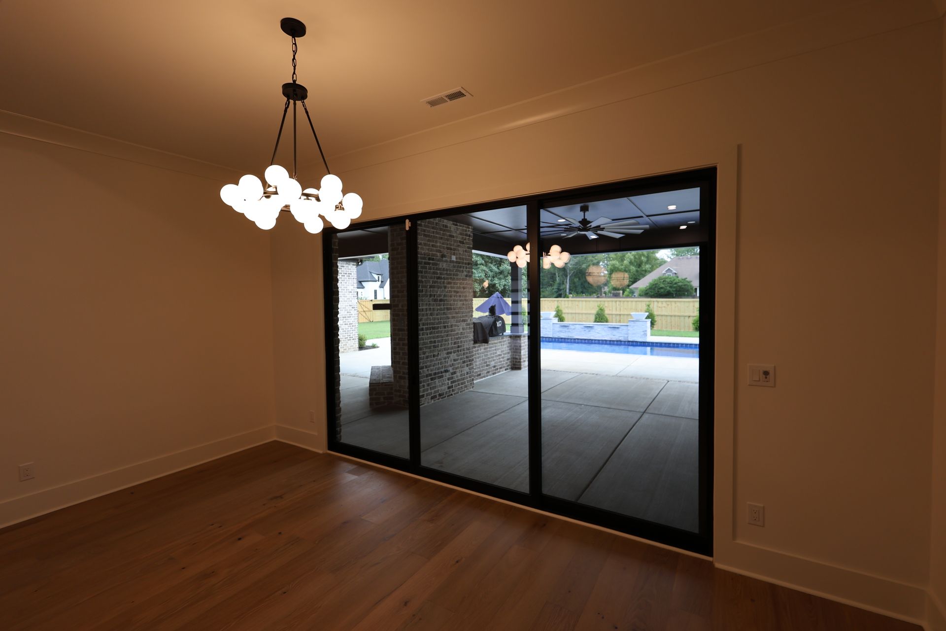 Dining room with a chandelier, large glass doors, and a view of a pool.