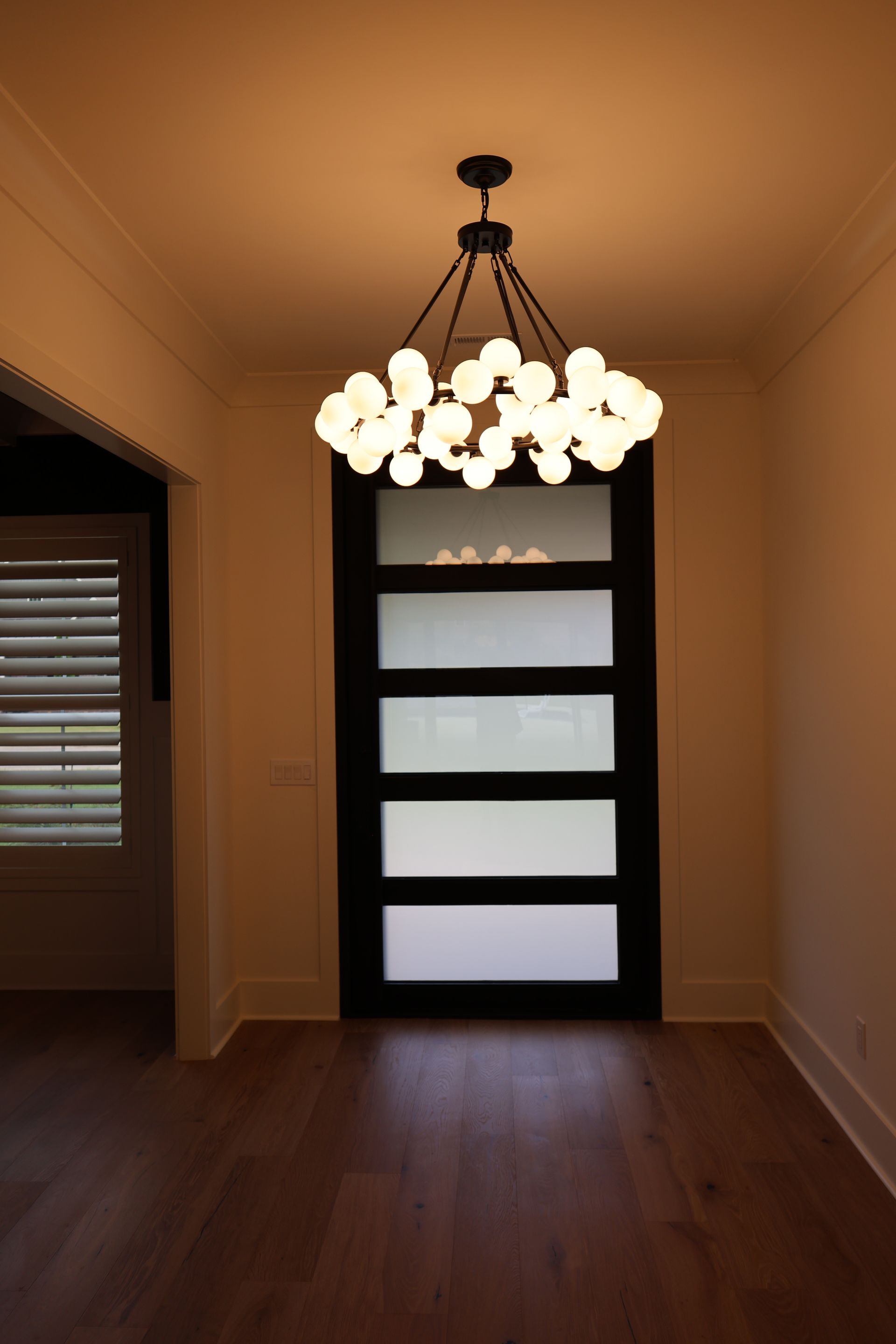 Dining room with dark wood door and modern globe chandelier.