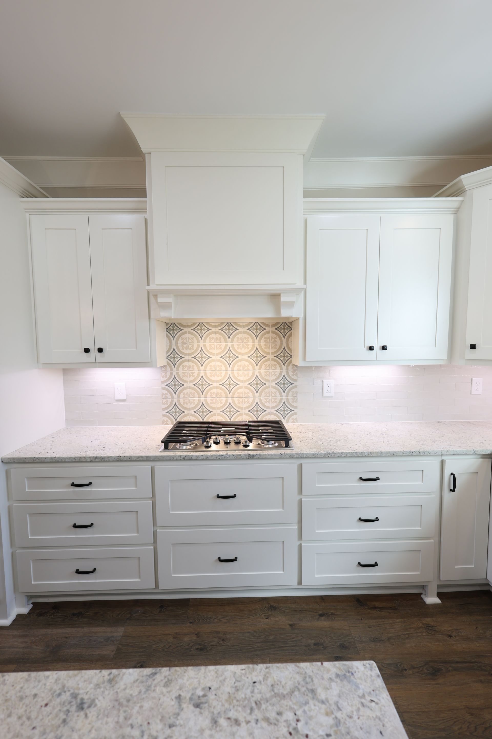 White kitchen with granite countertops, range, and cabinets.