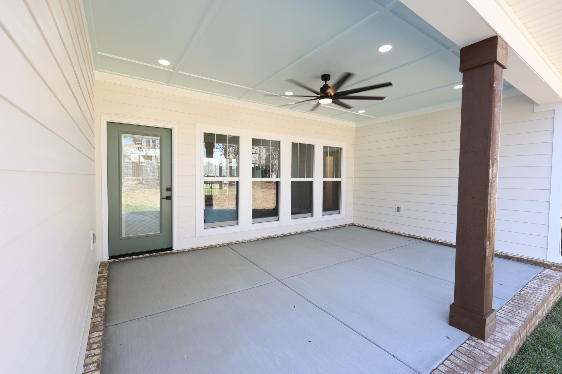 Covered patio with blue ceiling, windows, and dark brown support beam.