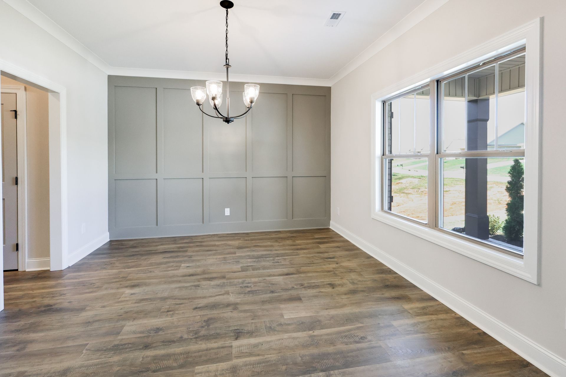 Dining room with gray accent wall, chandelier, and large window.