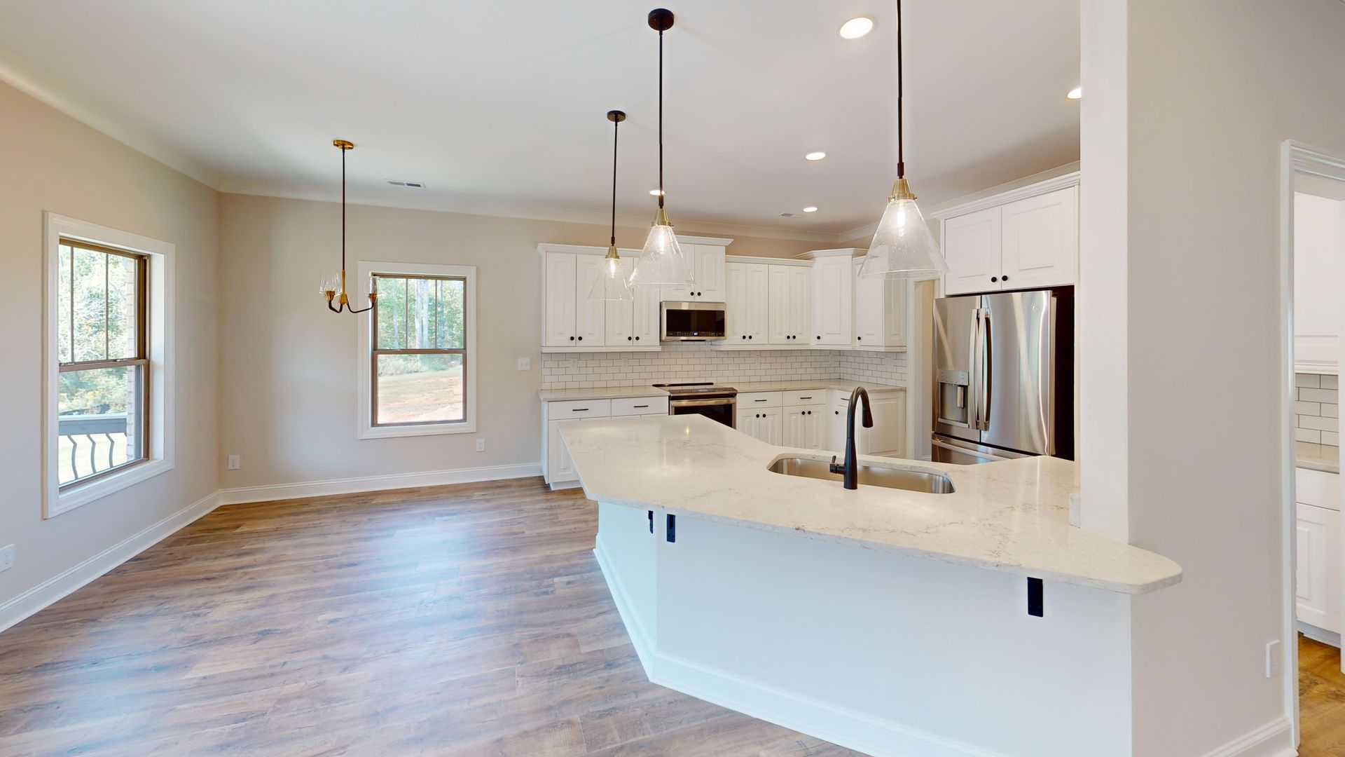 Kitchen with white cabinets, island, and stainless steel appliances. Hardwood floors and pendant lights.