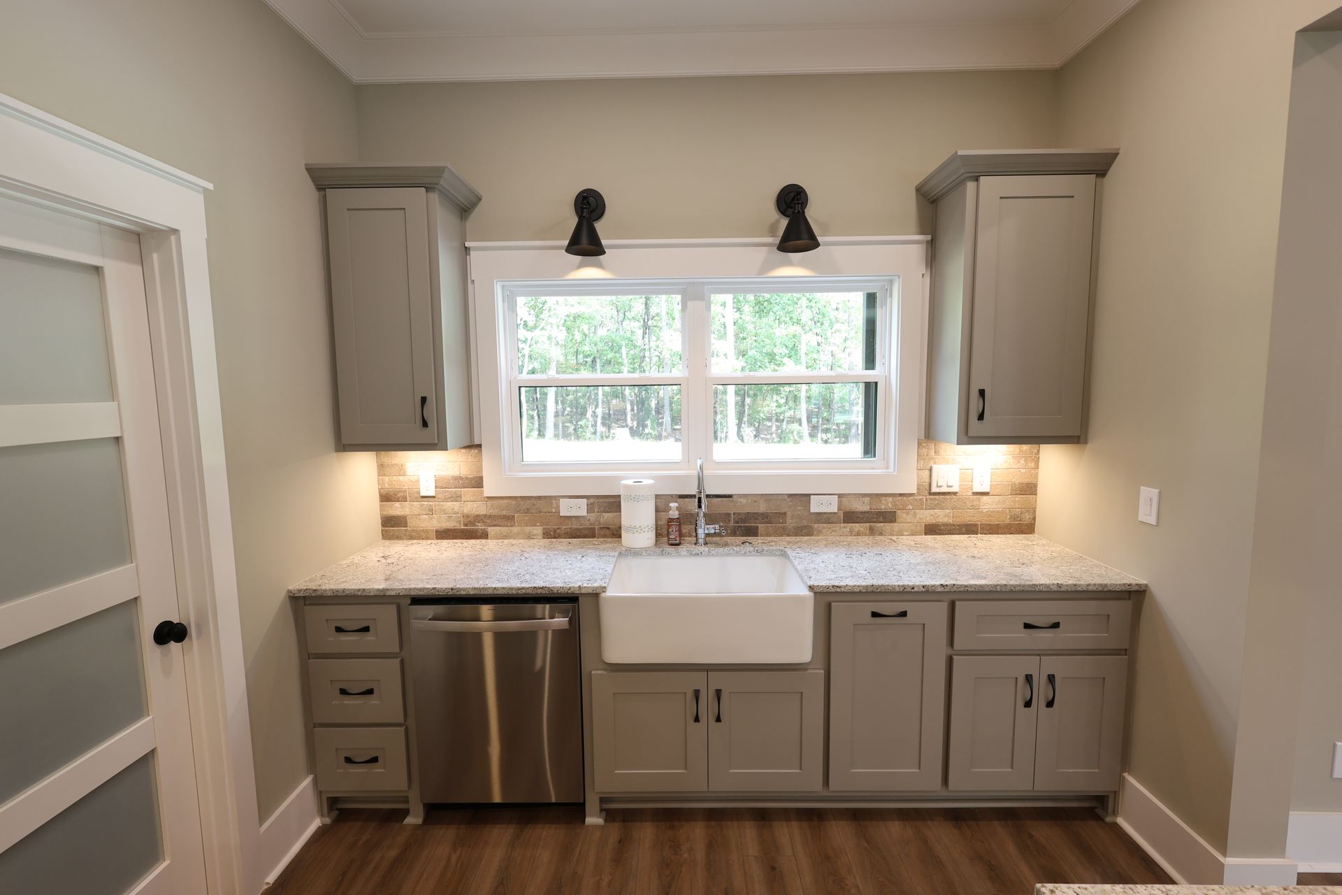 Kitchen with gray cabinets, a stainless steel dishwasher, and a white farmhouse sink.