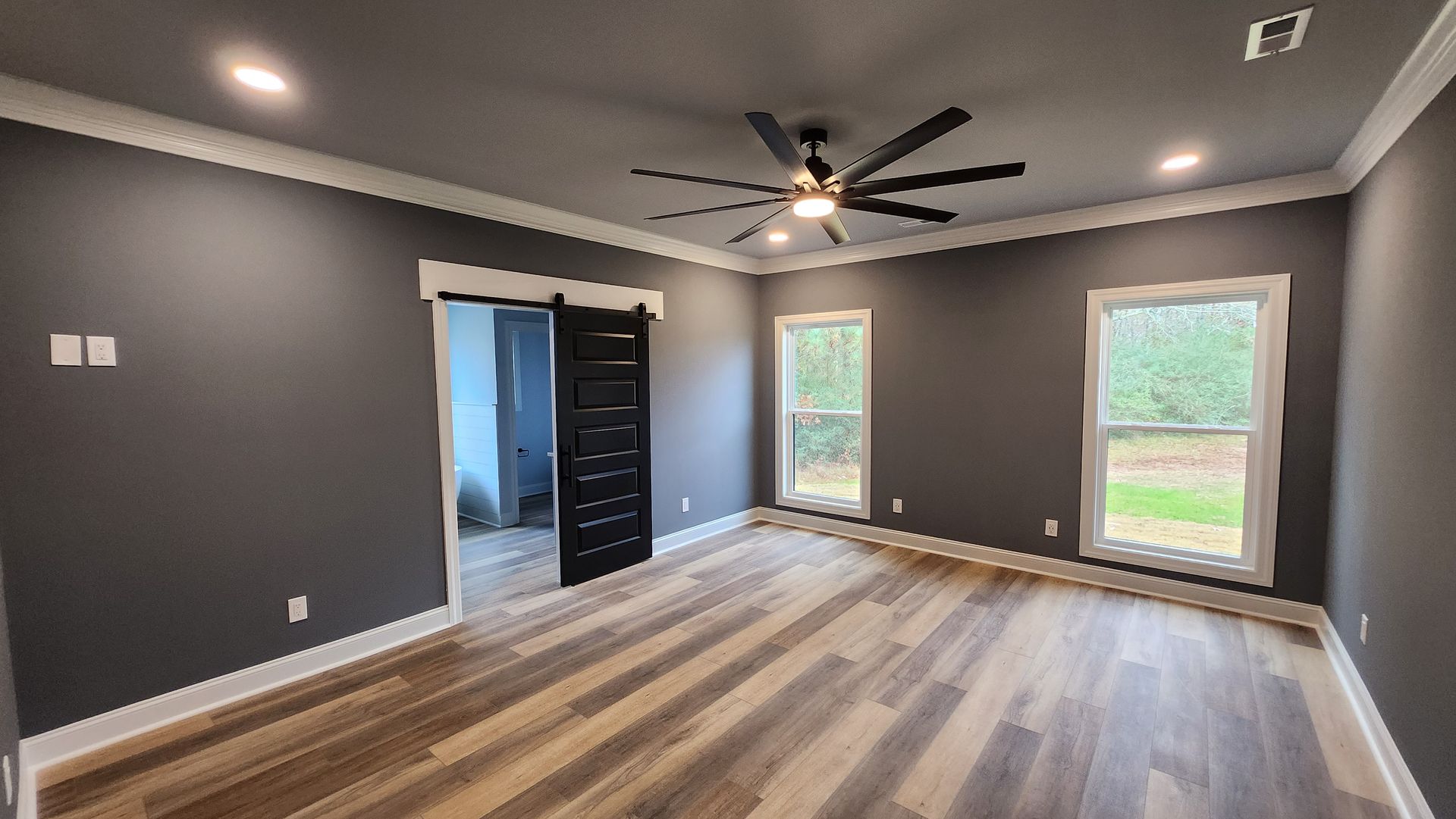 Bedroom with dark gray walls, light wood-look floor, and a black sliding door.