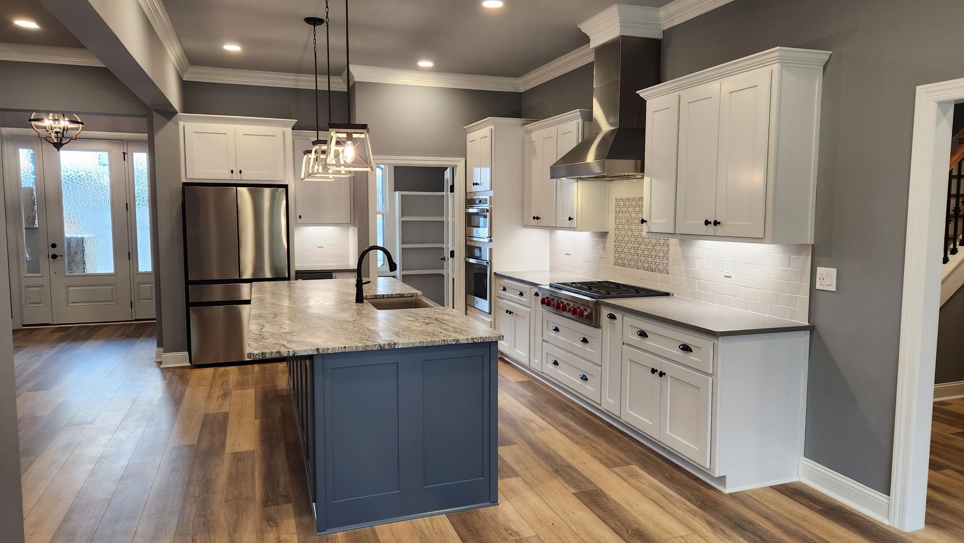 Modern kitchen with white cabinets, gray walls, stainless steel appliances, and a blue island.